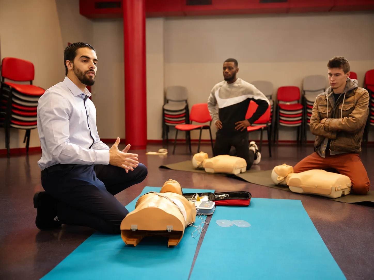 Mehdi Joyen anime une session de secourisme devant un groupe d'apprenants et leurs mannequins d'exercice