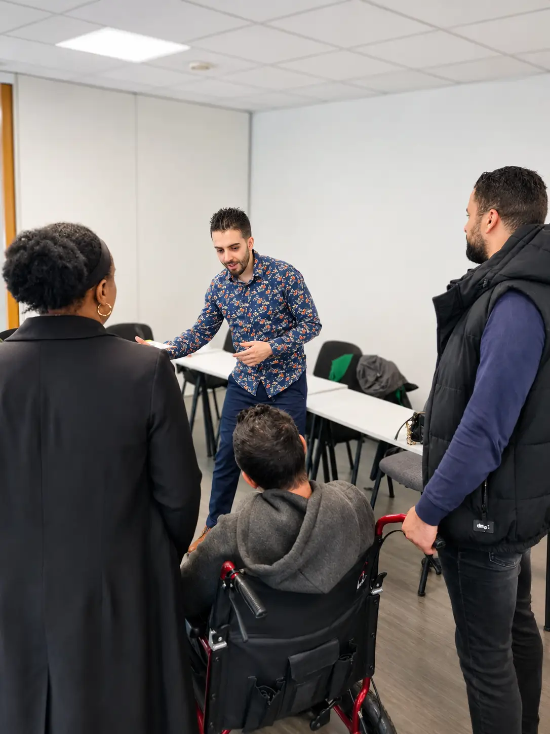 Un formateur TPMR anime une session en salle, un apprenant en fauteuil roulant au centre du groupe