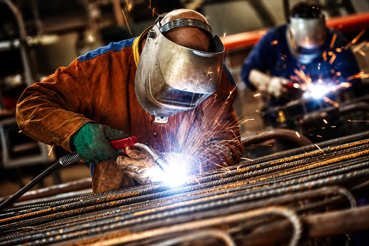 Travaux par point chaud : soudeurs à l’œuvre sous les étincelles, casque de protection baissé