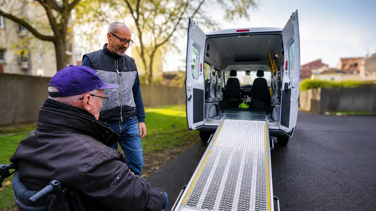 Conducteur accompagnateur déployant la rampe d’un véhicule TPMR devant un passager en fauteuil roulant