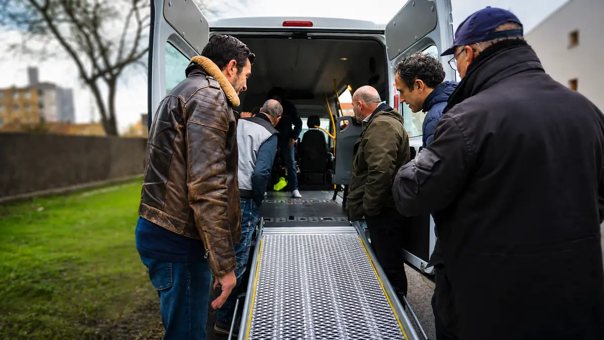 Groupe d’apprenants autour de la rampe d’un véhicule TPMR pendant une session de formation en présentiel